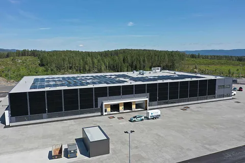 Stor grå bygning med solcellepanel på taket